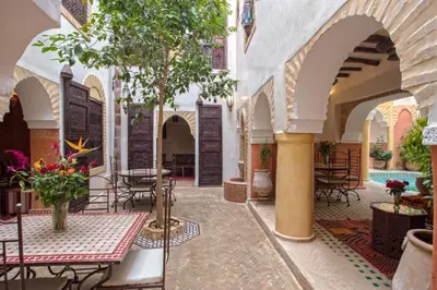 a courtyard with tables and chairs and a tree at Riad Itrane in Marrakech