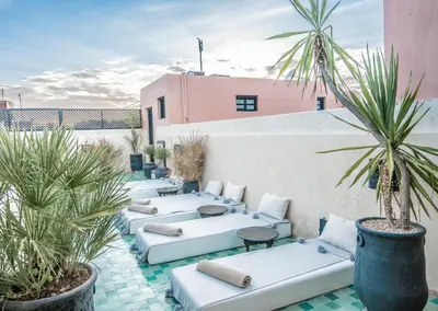 a row of chaise lounges and palm trees on a patio at Riad Spa Sindibad in Marrakech