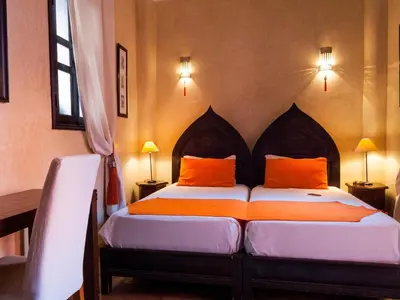 a bedroom with a bed with orange pillows at Riad Aderbaz in Marrakech