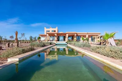 a home with a pool in front of a house at La villa Kela Serene 4 suites in Marrakech