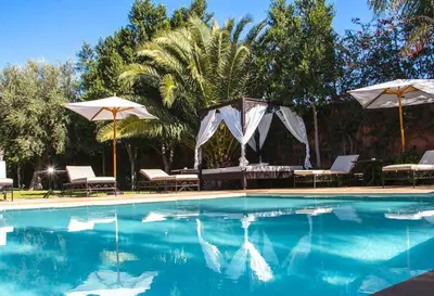 a swimming pool with umbrellas and chairs and a table at Palais El Miria & SPA in Dar Caïd Layadi