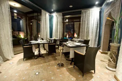 a dining room with tables and chairs and curtains at Palais El Miria & SPA in Dar Caïd Layadi