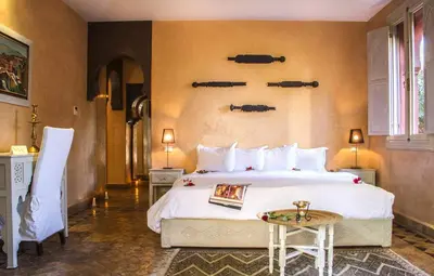 a bedroom with a large white bed and a table at Palais El Miria & SPA in Dar Caïd Layadi