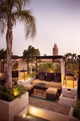 a patio with a couch and a table and a palm tree at Les Jardins De La Koutoubia in Marrakech