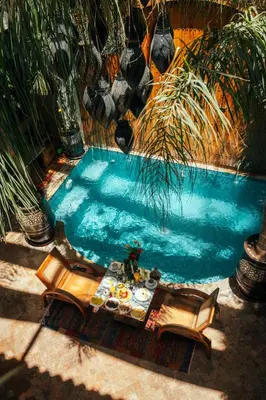 a table and chairs next to a swimming pool at Riad Anya & SPA in Marrakech