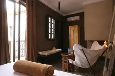 a bedroom with a bed and a chair and a window at Ambre Epices Medina Riad in Marrakech