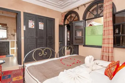 a bedroom with a bed in a room with windows at Riad Losra in Marrakech