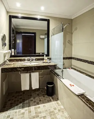 a bathroom with a sink and a tub and a mirror at Palm Plaza Marrakech in Marrakech