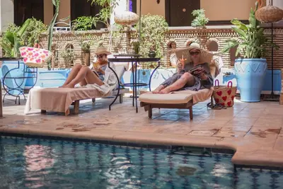 two people sitting in chairs next to a swimming pool at Amani Hotel Suites & Spa in Marrakech