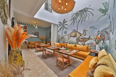 a restaurant with orange furniture and a mural of animals at Riad Anyssates in Marrakech