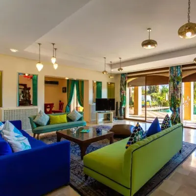 a living room with a green couch and blue chairs at Palais les sources de l'atlas, Padel & spa in Marrakech