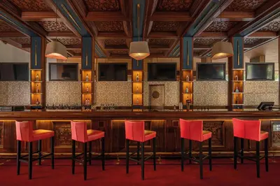 a bar with red stools in a room at Es Saadi Marrakech Resort - Hotel in Marrakech
