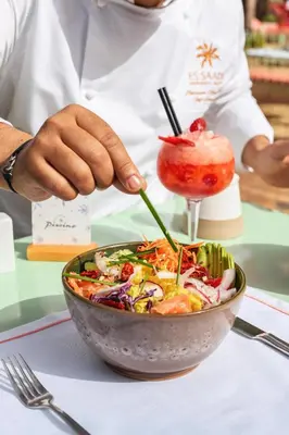 a person is preparing a salad in a bowl at Es Saadi Marrakech Resort - Hotel in Marrakech