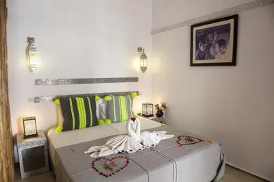 a room with a bed with a woman sitting on it at Riad De Vinci & SPA in Marrakech