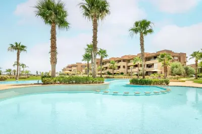 a swimming pool with palm trees in a resort at Résidence Golfique PJ, jardin, piscine in Marrakech
