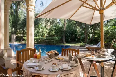 a table with food and an umbrella on a patio at Es Saadi Marrakech Resort - Palace in Marrakech