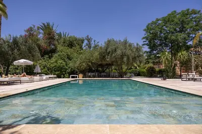 a swimming pool in a yard with chairs and trees at Villa Al Assala Palmeraie in Marrakech