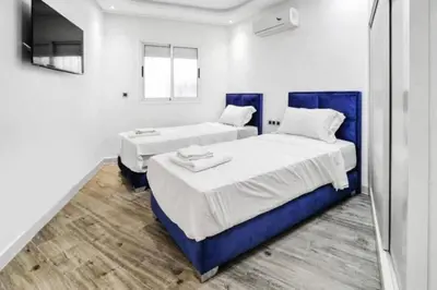a bedroom with two beds and a television in it at Magnifique appartement en plein centre ville in Marrakech