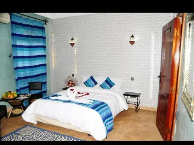 a bedroom with a large white bed with blue pillows at Riad Mhidou Marrakech in Marrakech