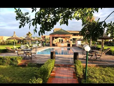 a resort with a pool and tables and chairs at Riad Mhidou Marrakech in Marrakech