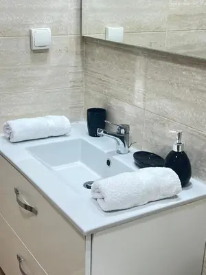 a bathroom sink with two towels and a mirror at Marrakech Prestigia appartement vue piscine golf endroit calme in Marrakech