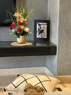 a shelf with a vase of flowers and a picture at Super appartement familial avec piscine à Prestigia Marrakech in Marrakech