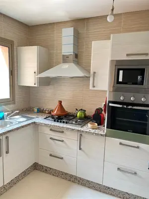 a kitchen with white cabinets and a stove top oven at Super appartement familial avec piscine à Prestigia Marrakech in Marrakech