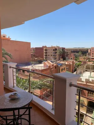 a balcony with a table and a view of a city at Résidence Las Palmeras in Marrakech