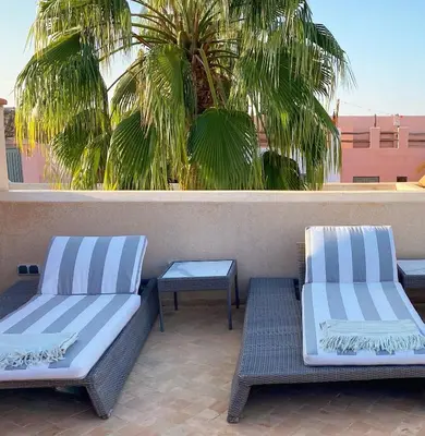 two blue and white benches on a patio with a palm tree at Riad Rossi in Marrakech
