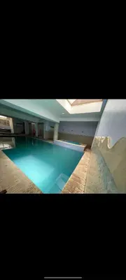a swimming pool with blue water in a building at Cosy apartment in Marrakesh, Guliz in Marrakech