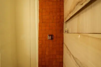a bathroom with a shower with a red tiled wall at Cosy Appartement 5min de Majorelle in Marrakech
