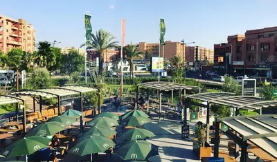 a group of tables with green umbrellas in a city at Royal Deluxe Platinum - Marrakech, Luxe Pool View in Marrakech